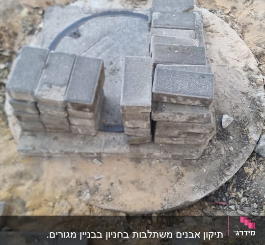 אבנים מונחות על מכסה עגול באתר בנייה